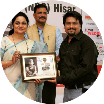 Man in a black shirt receiving a framed "Token of Love" plaque from Lok Nirman NGO representatives in Hisar.